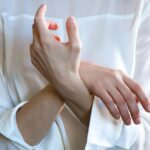 Elegant hands in a white shirt gently touching each other, symbolizing calm and tenderness.