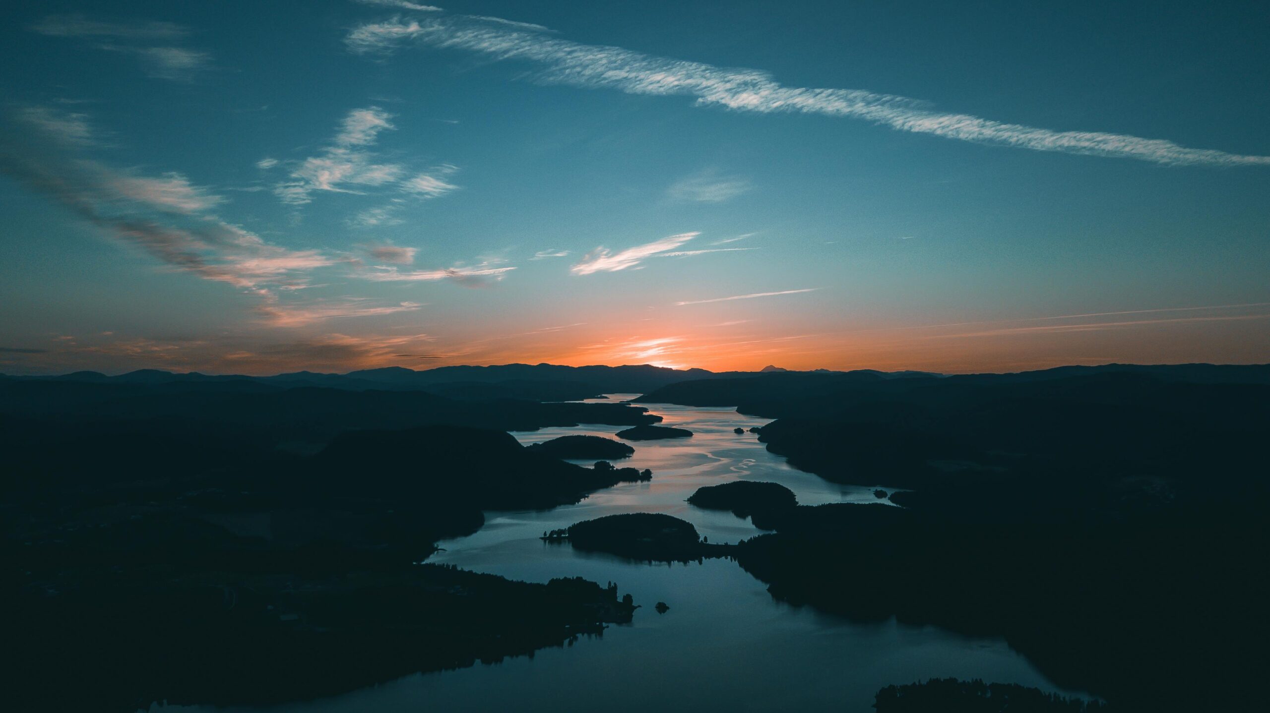 A breathtaking aerial shot showcasing a calm river winding through hills at sunset, with a vivid sky.