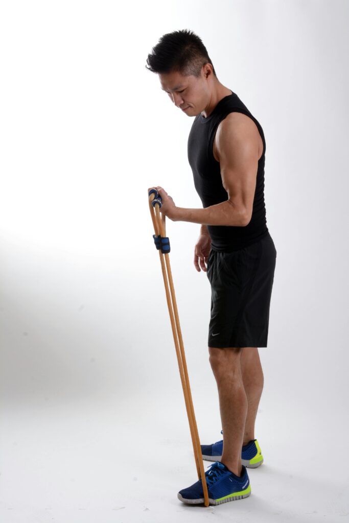 Athletic man using resistance band for workout in gym setting.