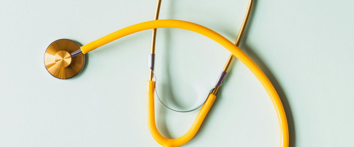 Top view of yellow medical stethoscope placed on white surface during coronavirus pandemic